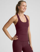 model wearing a red racerback tank top and leggings against a light gray background.